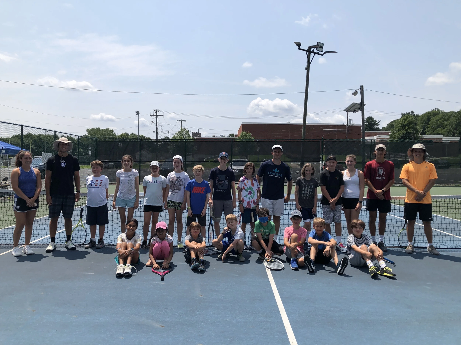 Summer camp group of First Serve Tennis students and coaches